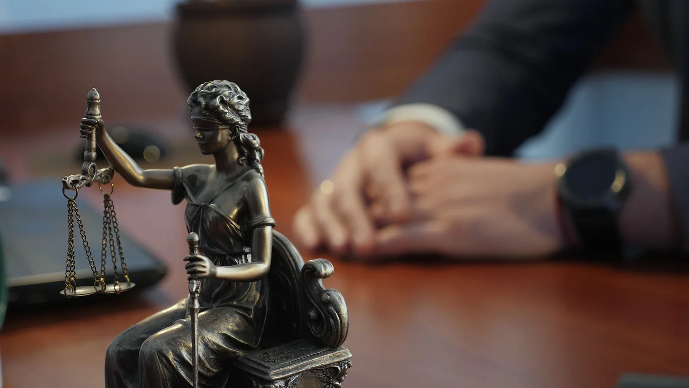 Statue of justice on the table against the background of the hand gestures of a man, a lawyer or a judge