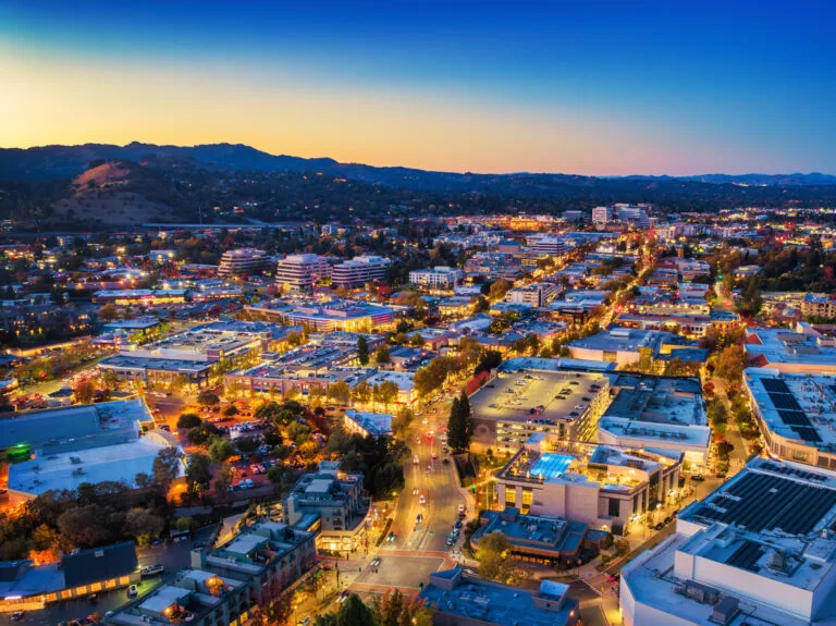 Downtown Walnut Creek aerial at dusk, with mountains and the sunset in the background. Walnut Creek is part of the San Francisco Bay Area.